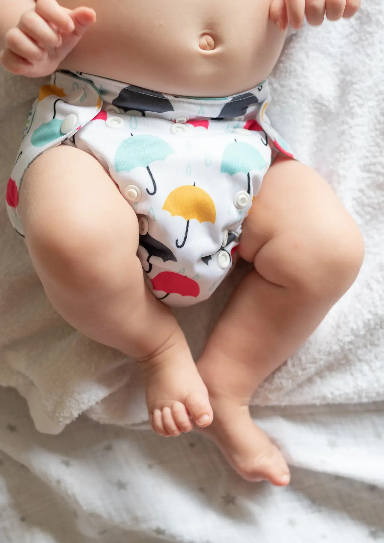 Ein Baby trägt eine mit Regenschirmen bedruckte Stoffwindel