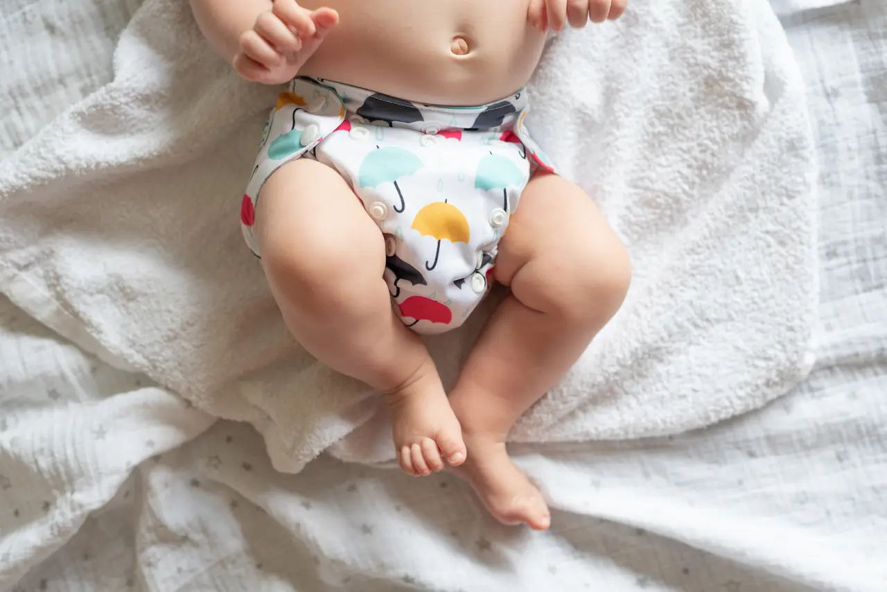 Ein Baby trägt eine mit Regenschirmen bedruckte Stoffwindel