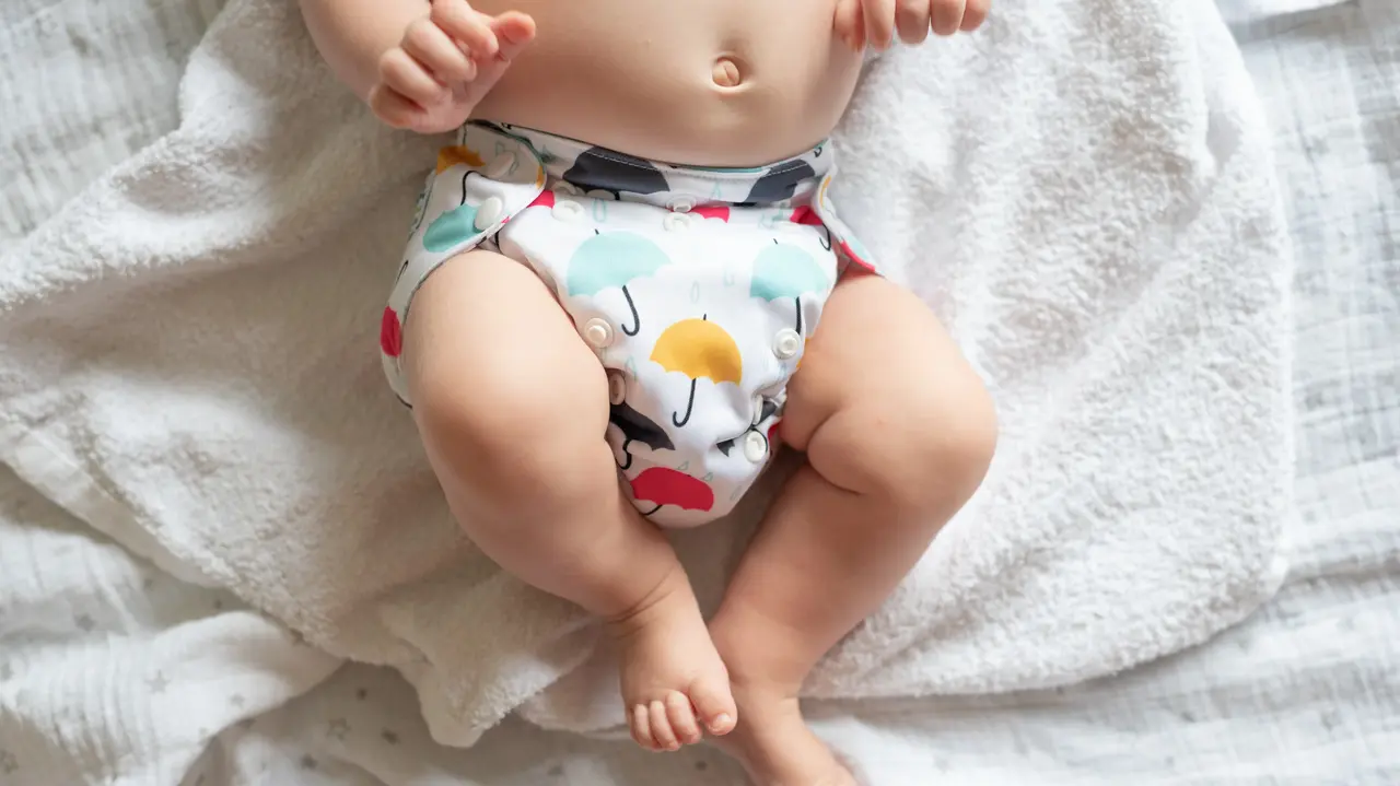 Ein Baby trägt eine mit Regenschirmen bedruckte Stoffwindel