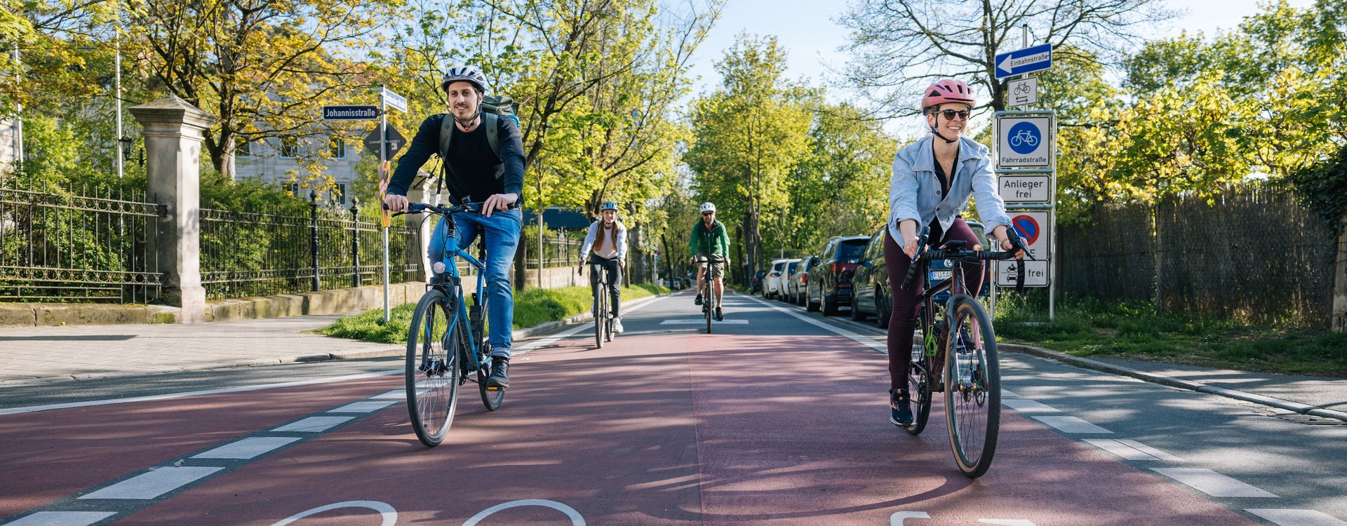 Mehrere Personen befahren die Fahrradstraße Dambacher Straße an einem sonnigen Tag.