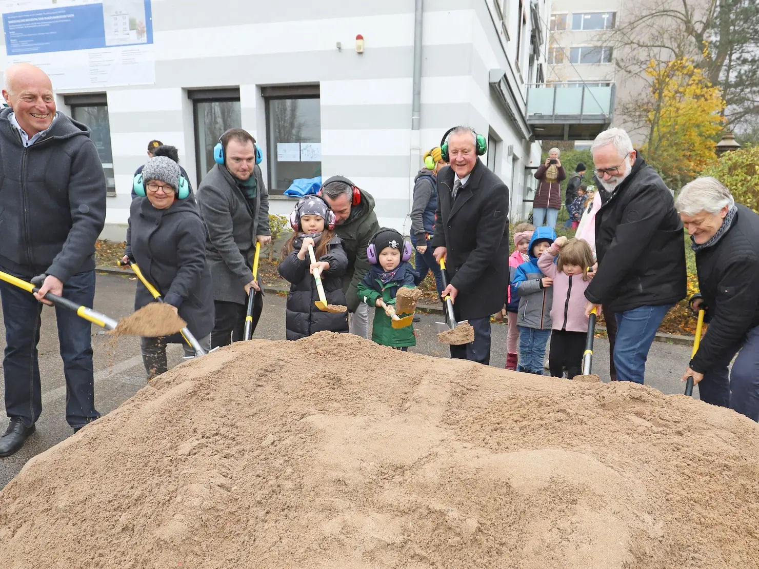 Oberbürgermeister Thomas Jung, Mitarbeitende des Rundfunkmuseums und Kinder stechen mit Schaufeln in einen Erdhügel vor dem Rundfunkmuseum. Klick öffnet Bild in größerer Ansicht.