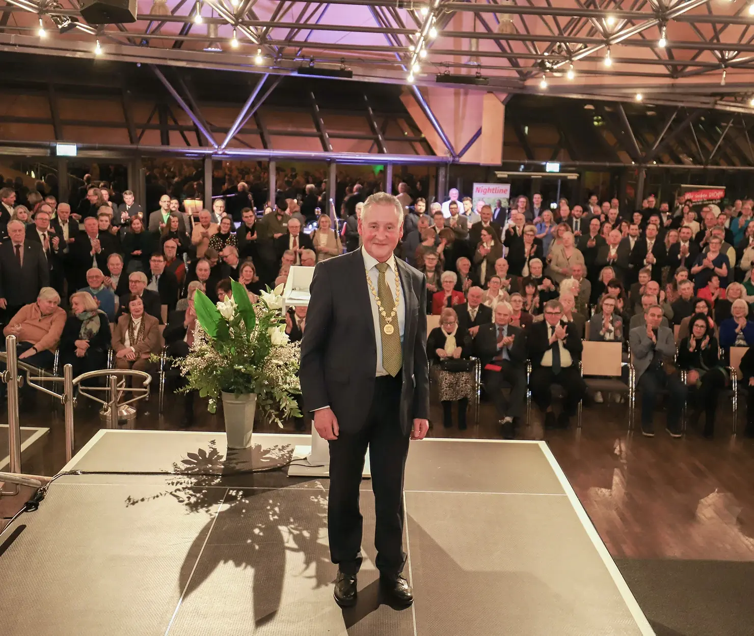 OB Jung auf der Bühne, das Publikum im Hintergrund; Klick öffnet Bild in größerer Darstellung.