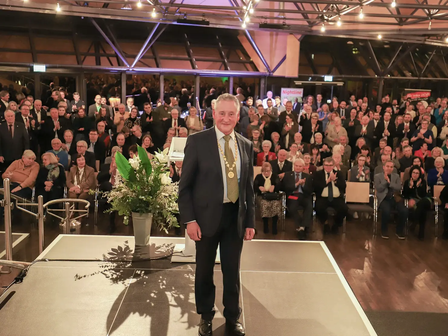 OB Jung auf der Bühne, das Publikum im Hintergrund; Klick öffnet Bild in größerer Darstellung.