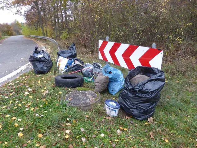 Säcke, ein Eimer Farbe, Tüten und ein Autoreifen am Straßenrand