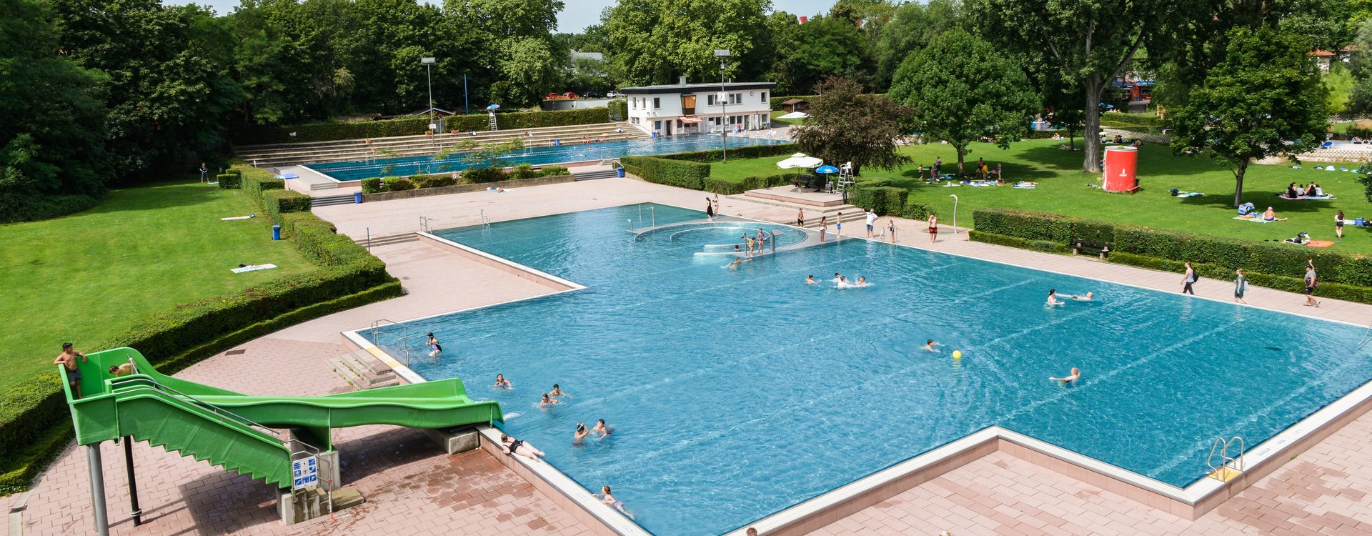 Außenbereich des Sommerbad Fürth mit Rutsche, Becken und Badegästen