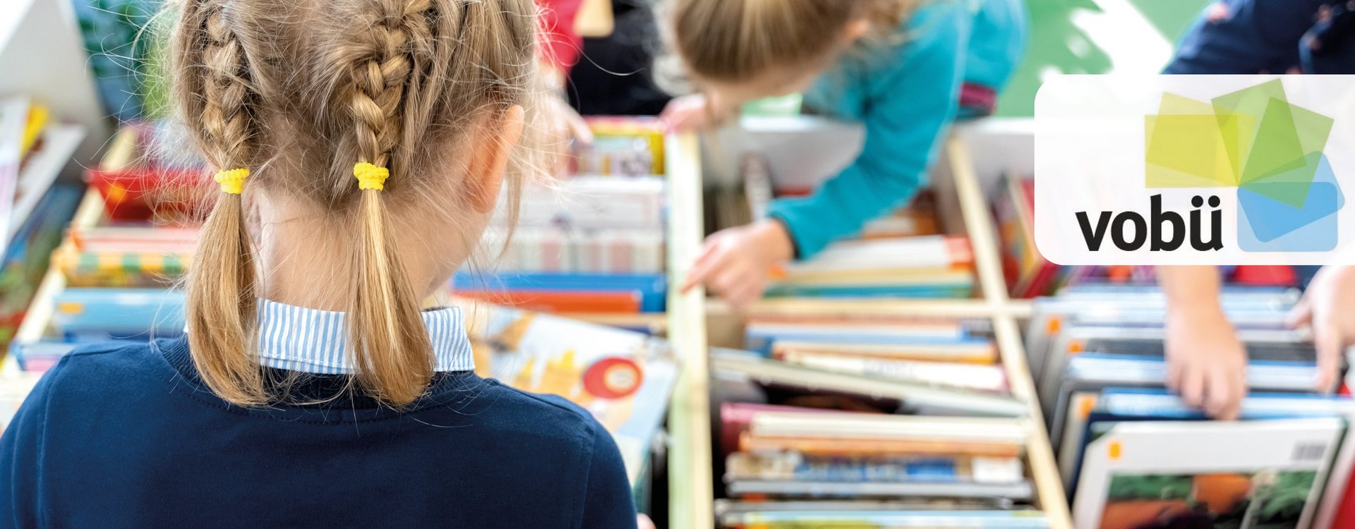 Mädchen suchen in einer Bücherkiste eifrig nach Lesestoff.