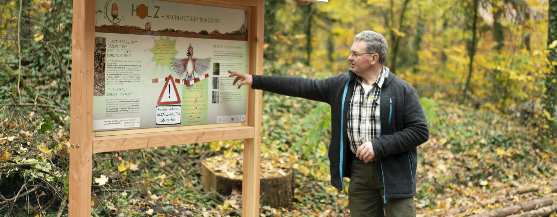 Stadtförster zeigt auf Schild am Waldlehrpfad