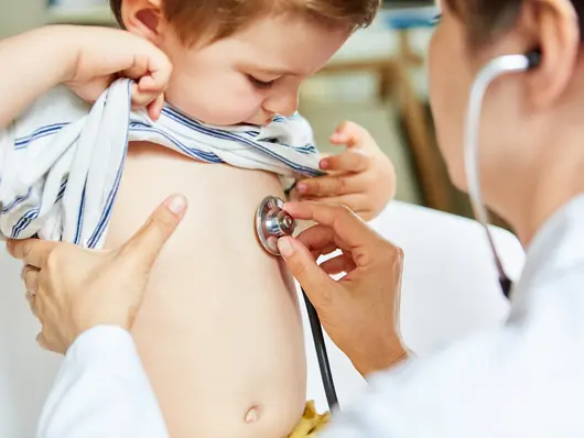 Kinderärztin beim Abhören einer Lunge vom Kind mit Stethoskop. Klick öffnet Bild in größerer Ansicht.