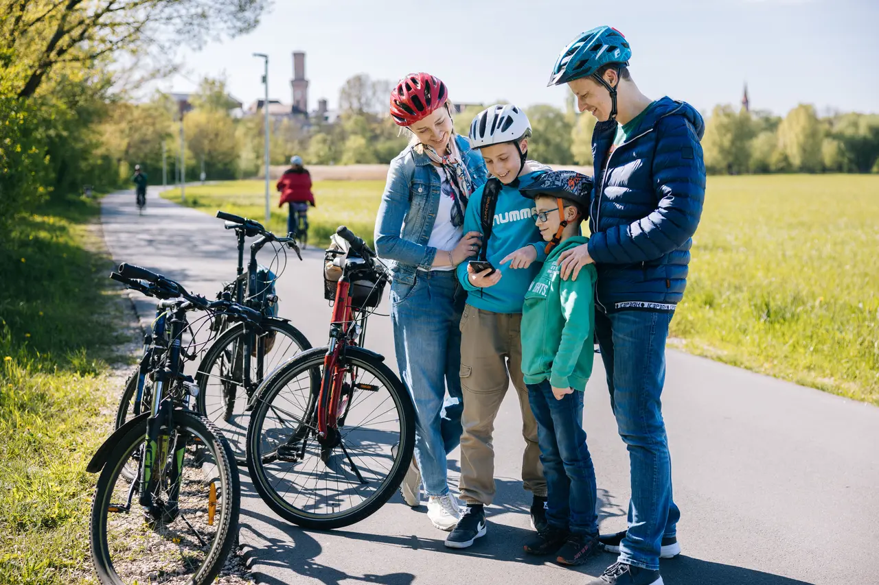 Familie hält am Wiesengrund am Wegrand mit Fahrrädern