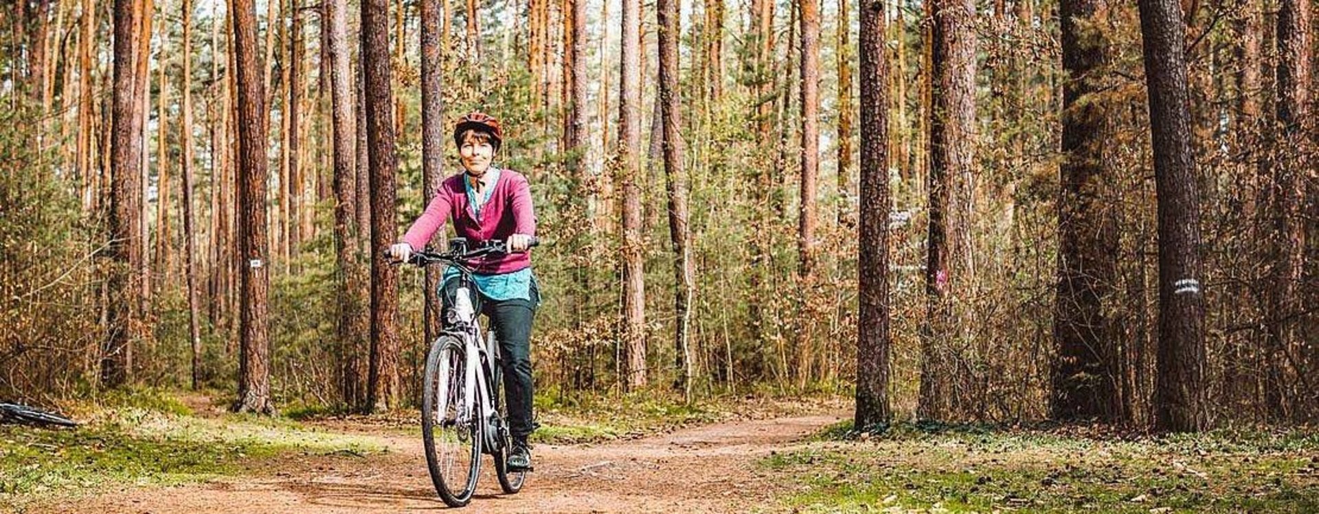 Eine Frau fährt auf dem Fahrrad durch den Stadtwald