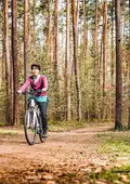 Eine Frau fährt auf dem Fahrrad durch den Stadtwald