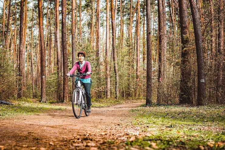 Eine Frau fährt auf dem Fahrrad durch den Stadtwald