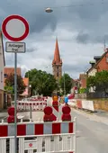 Die Baustelle mit Absperrungen und dem Kirchturm im Hintergrund.