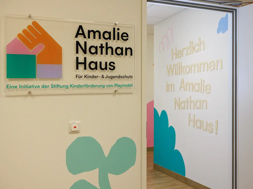 Eingangsbereich des Amalie Nathan Hauses mit farbenfrohem Logo und dem Schriftzug "Herzlich willkommen im Amalie Nathan Haus!" an der Wand. Klick öffnet Bild in größerer Ansicht.