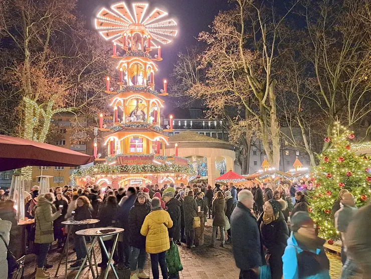 Pyramide auf dem Weihnachtsmarkt mit Menschenmassen im Vordergrund.