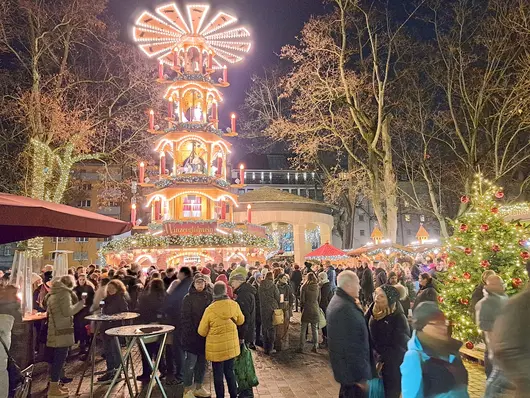 Pyramide auf dem Weihnachtsmarkt mit Menschenmassen im Vordergrund.