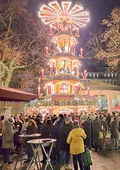 Pyramide auf dem Weihnachtsmarkt mit Menschenmassen im Vordergrund.