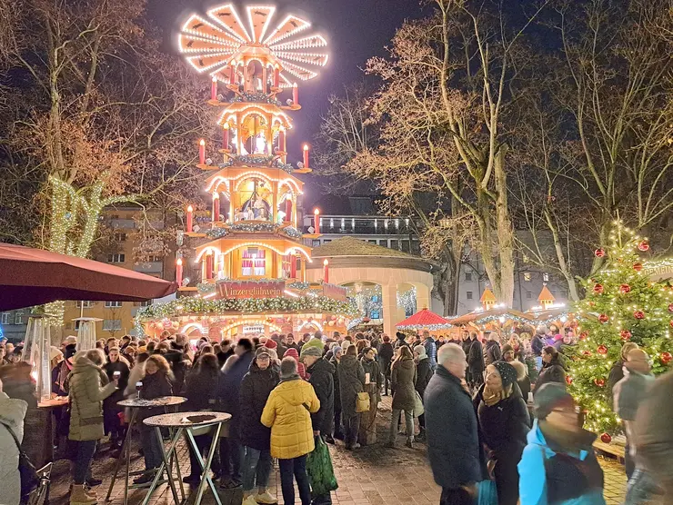 Pyramide auf dem Weihnachtsmarkt mit Menschenmassen im Vordergrund.