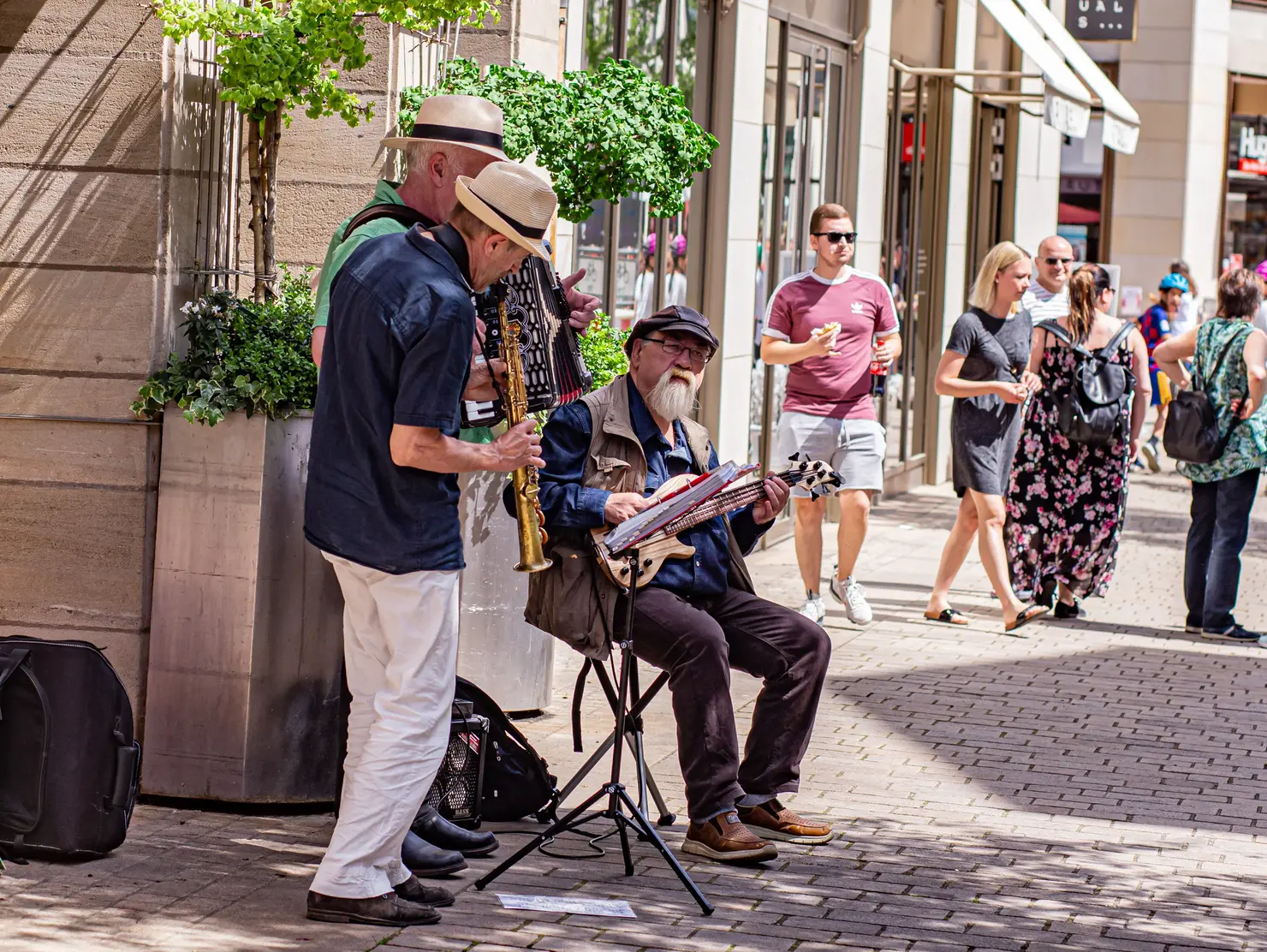 Drei Straßenmusiker spielen Bassgitarre, Akkorrdeon und Klarinette.