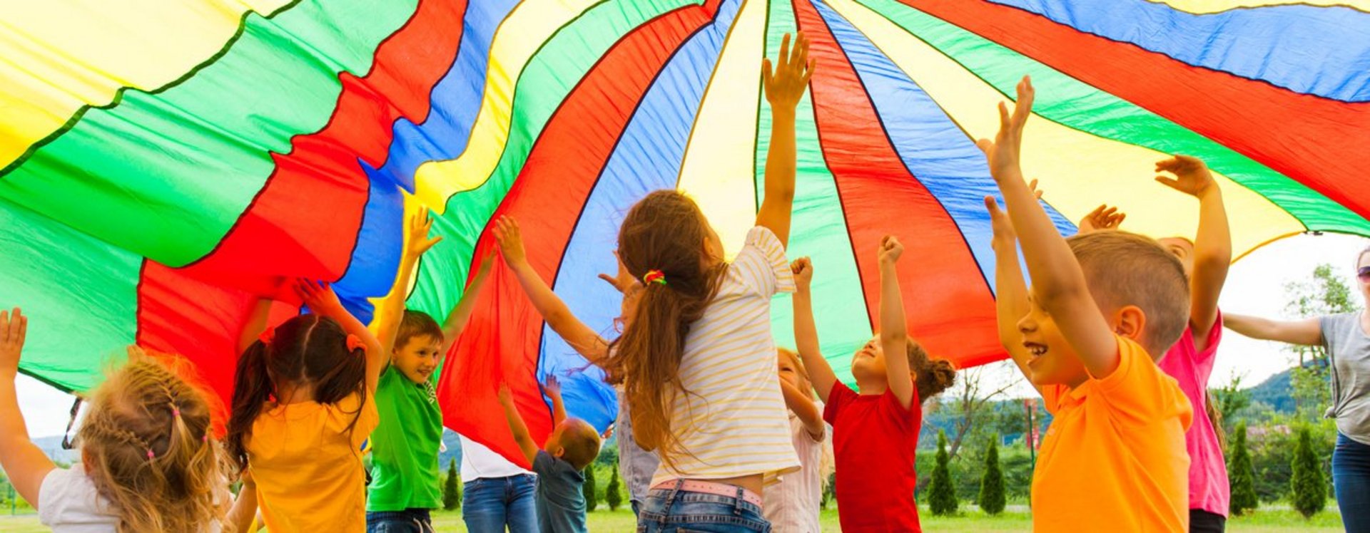 Lachende Kinder halten eine gestreifte Zeltplane in die Höhe