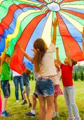 Lachende Kinder halten eine gestreifte Zeltplane in die Höhe