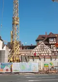 An einer Baustelle mit Kran wurde der Bauzaun von Kindern mit großformatigen Bildern gestaltet.