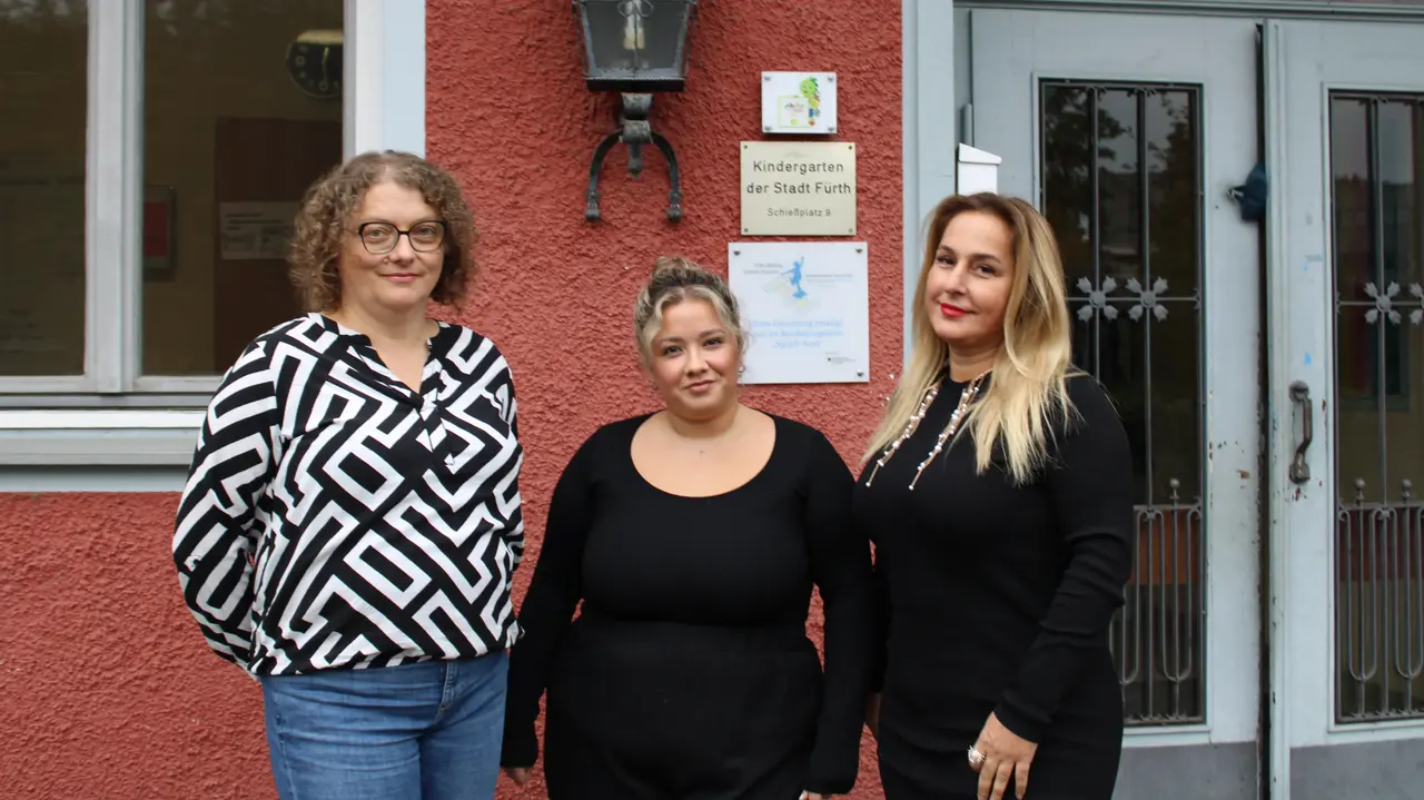 Drei Frauen vor einem rot gestrichenen Gebäude. Klick öffnet Bild in größerer Ansicht.