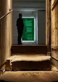 Blick über eine historische Treppe in die Dauerausstellung mit beleutetem Display.