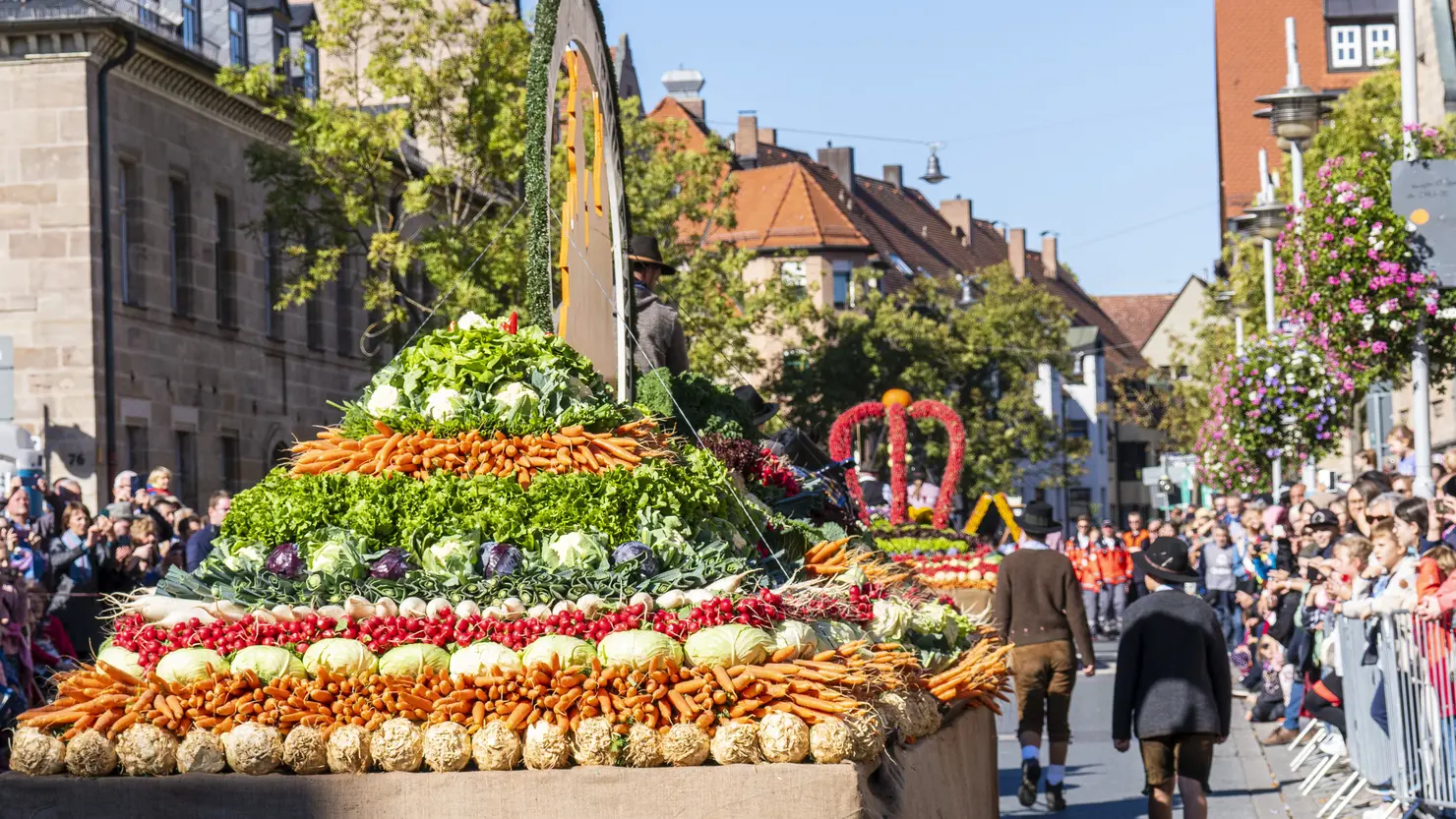 Geschmückter Gemüsewagen und Zuschauer bei sonnigem Wetter beim Erntedankfestzug 2022