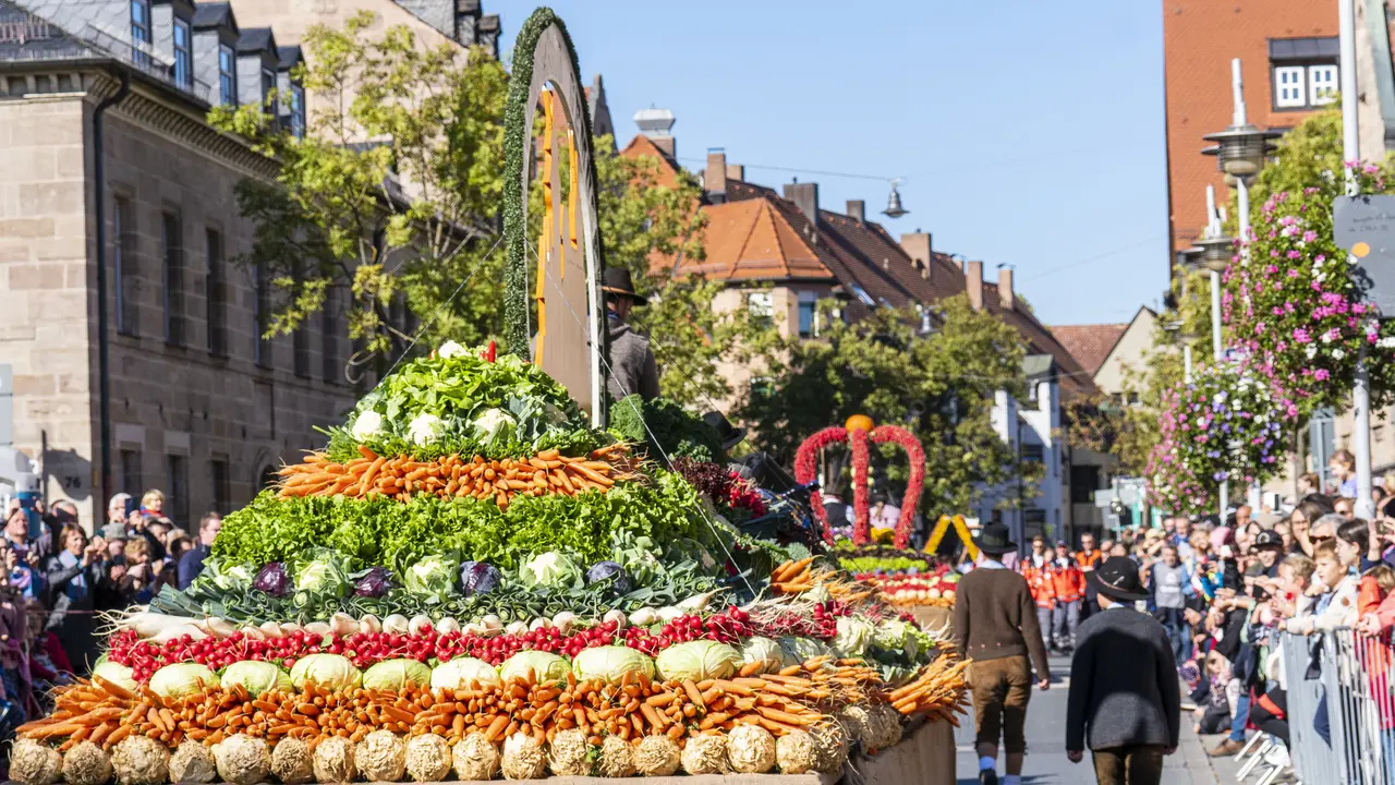 Geschmückter Gemüsewagen und Zuschauer bei sonnigem Wetter beim Erntedankfestzug 2022