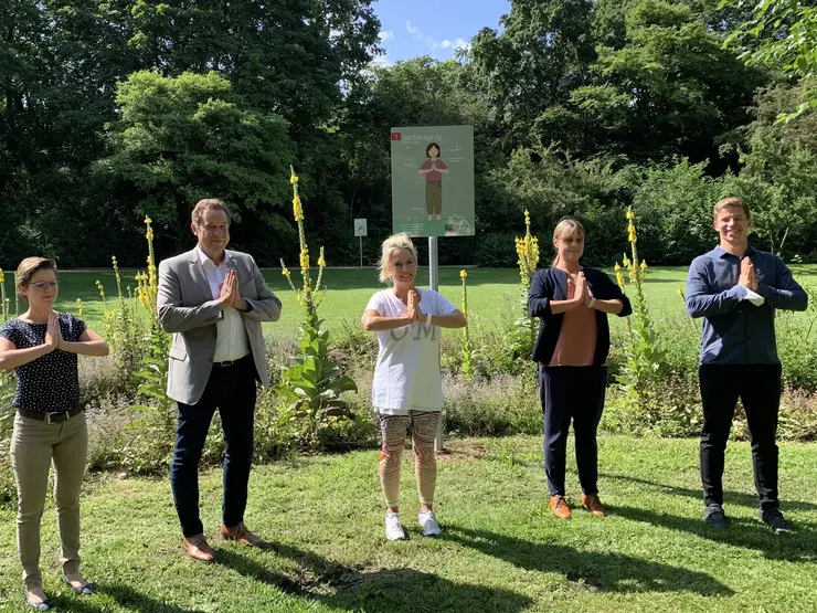 Bürgermeister Braun und Mitarbeitende der Stadt machen den Yoga-Gruß "Namaste", bei dem beide Hände im rechten Winkel aneinander gedrückt werden.