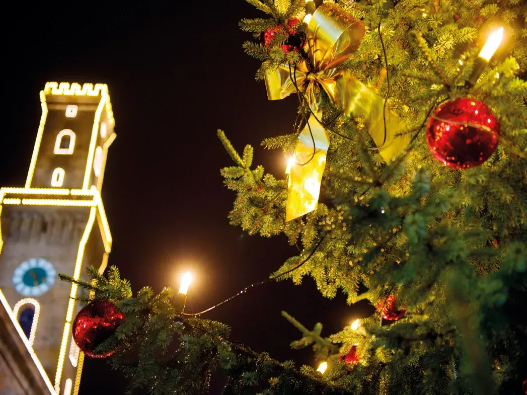 Weihnachtskugel an Baum in Nahaufnahme, Hintergrund zeigt das beleuchtete Rathaus; Klick zeigt Bild in größerer Darstellung