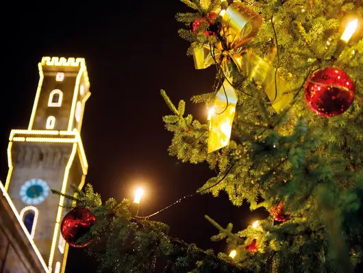 Weihnachtskugel an Baum in Nahaufnahme, Hintergrund zeigt das beleuchtete Rathaus; Klick zeigt Bild in größerer Darstellung