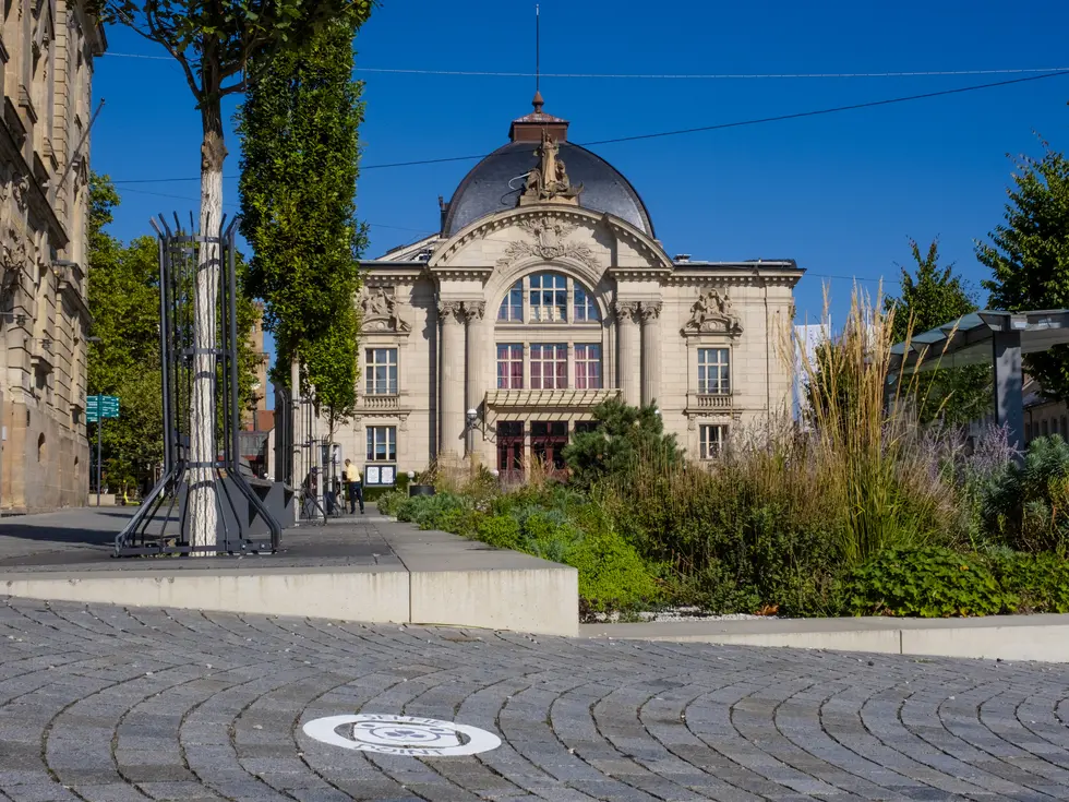 Selfie-Point als Aufkleber auf dem Boden mit dem Stadttheater im Hintergrund.