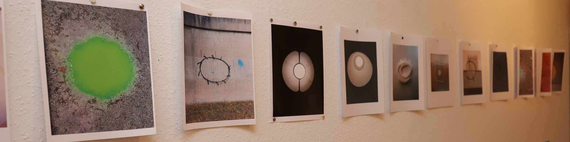 In einem Atelier hangen eine Reihe ungerahmter Bilder offensichtlich im Produktionsprozess.