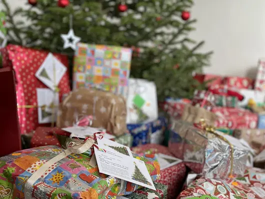 Verpackte Geschenke vor einem geschmückten Weihnachtsbaum