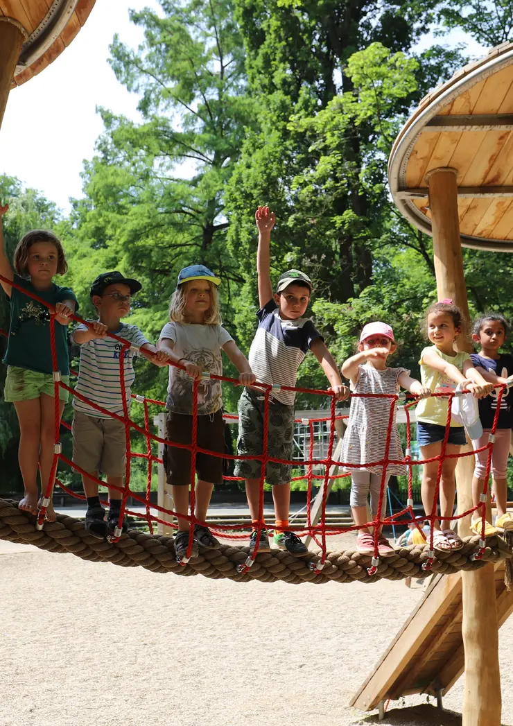 Kinder winken von einem Klettergerüst