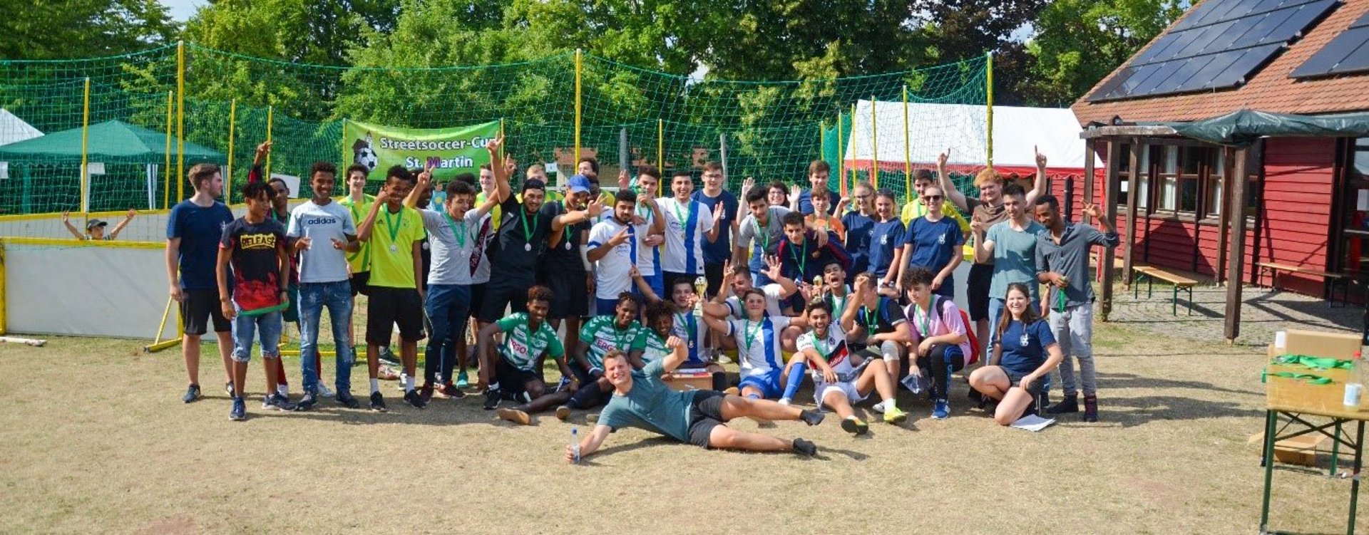 Die Teilnehmenden des Street-Soccer-Turniers posieren vor dem Spielfeld