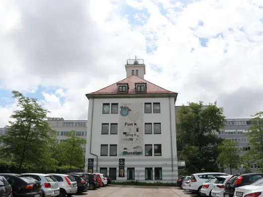 Rundfunkmuseum mit davor parkenden Autos. Klick öffnet Bild in größerer Ansicht.