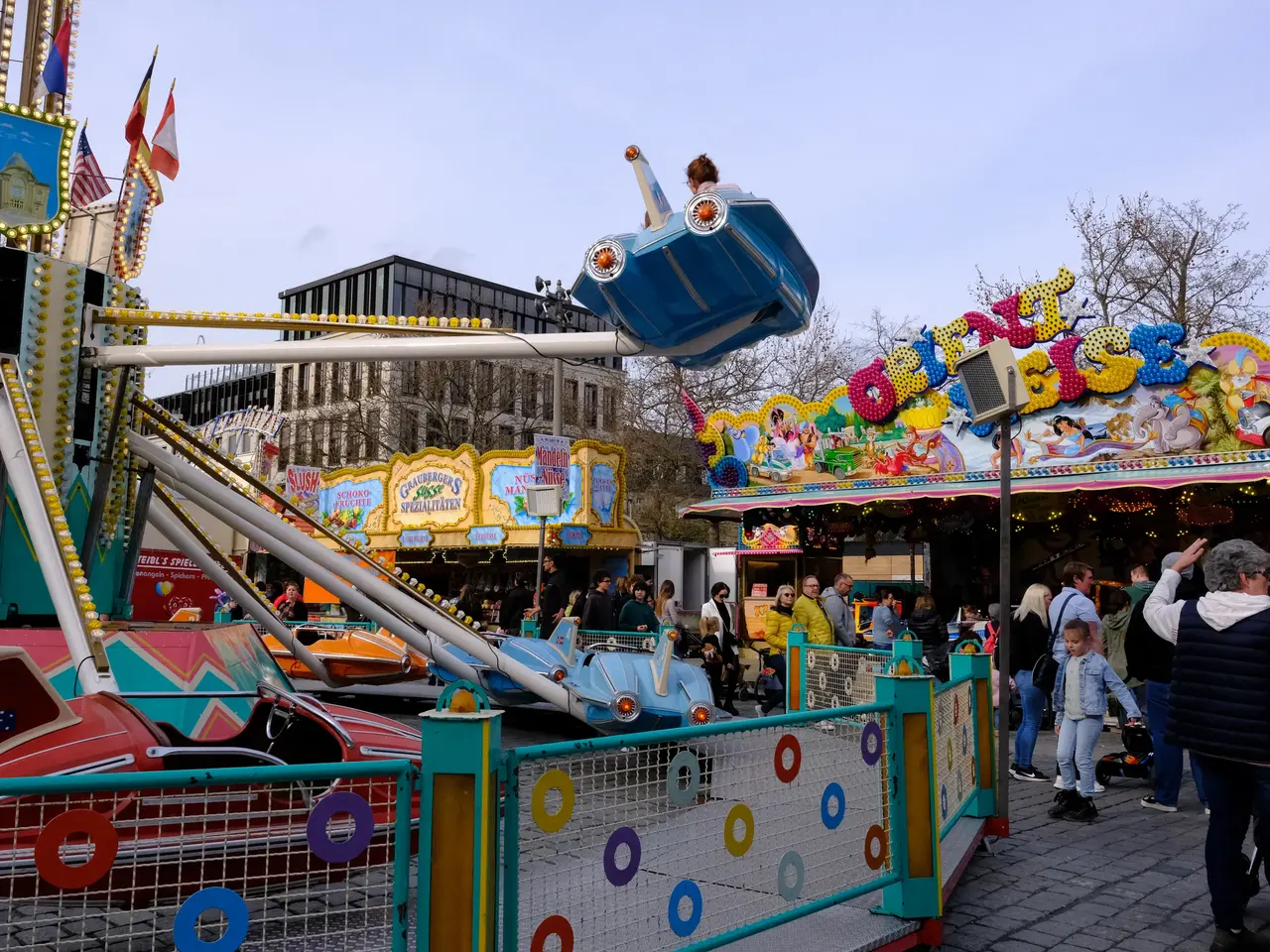 Fahrgeschäft und Menschen auf dem Frühlingsmarkt; Klick zeigt Bild in größerer Darstellung. 