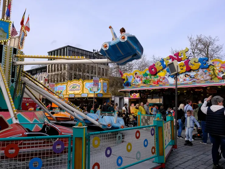 Fahrgeschäft und Menschen auf dem Frühlingsmarkt; Klick zeigt Bild in größerer Darstellung. 