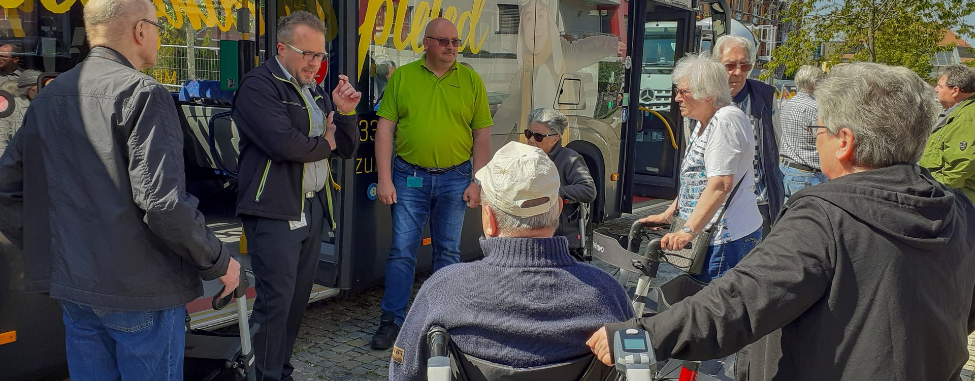 Seniorinnen und Senioren, teils im Rollstuhl, teils mit Rollator nehmen an einem Sicherheitstraining für öffentliche Verkehrsmittel teil.