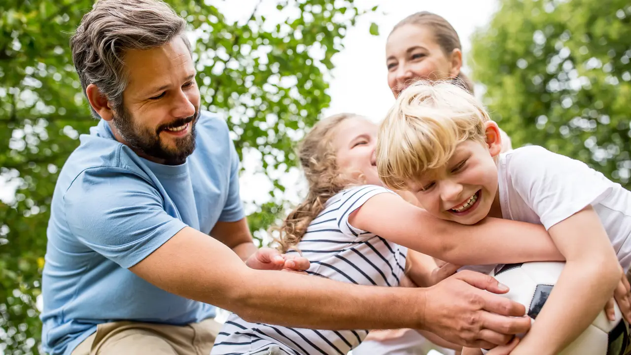 Glückliche Familie im Freien während sie mit einem Ball spielen