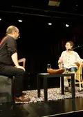 Moderator und Geschichtenerzähler Martin Ellrodt unterhält sich mit einer Teilnehmerin auf der Bühne des Kulturforums.