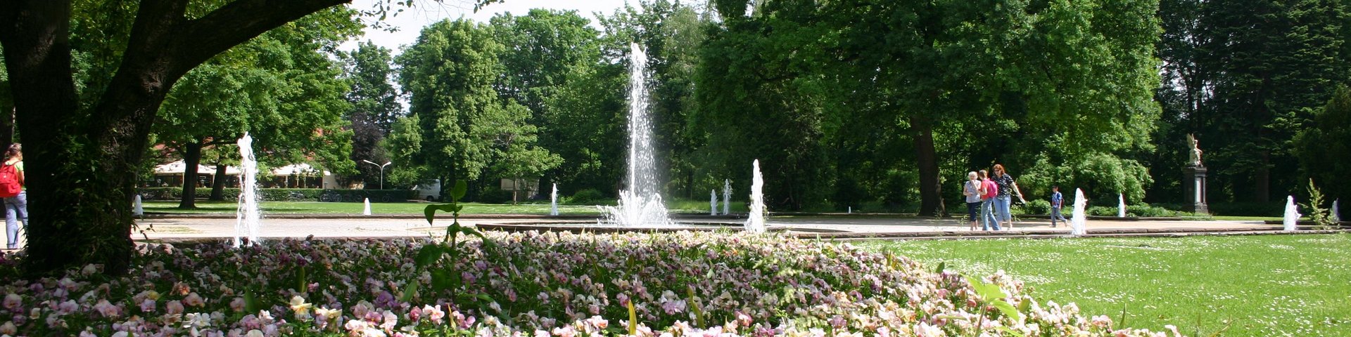 Springbrunnen im Stadtpark Fürth, im Vordergrund blühende Rabatten