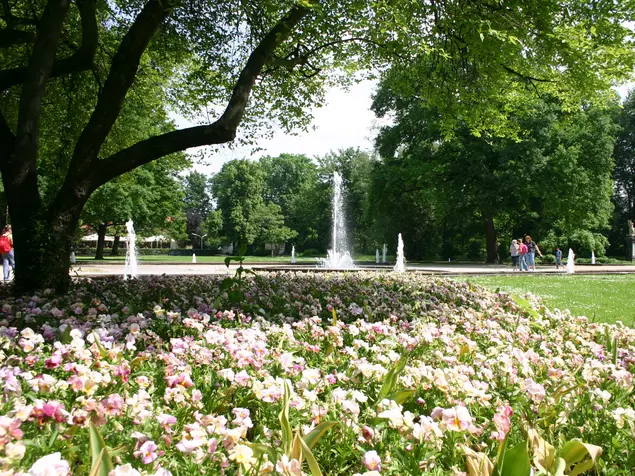 Springbrunnen im Stadtpark Fürth, im Vordergrund blühende Rabatten