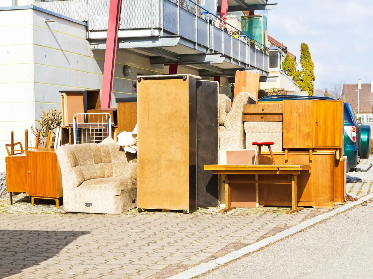 Sperrmüll Holzmöbel stehen auf einem Parkplatz vor einer Wohnanlage